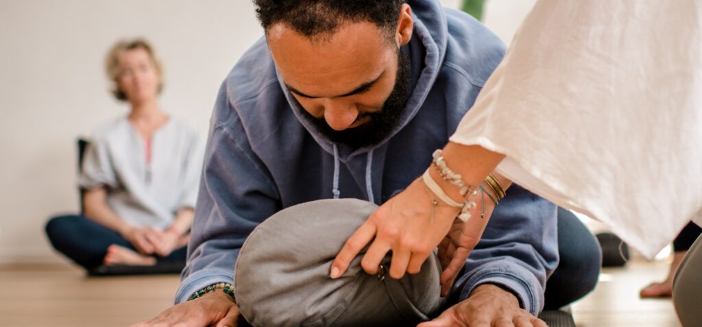 iemand die yoga beoefent met een kussen om zachtheid in de yoga practice te oefenen