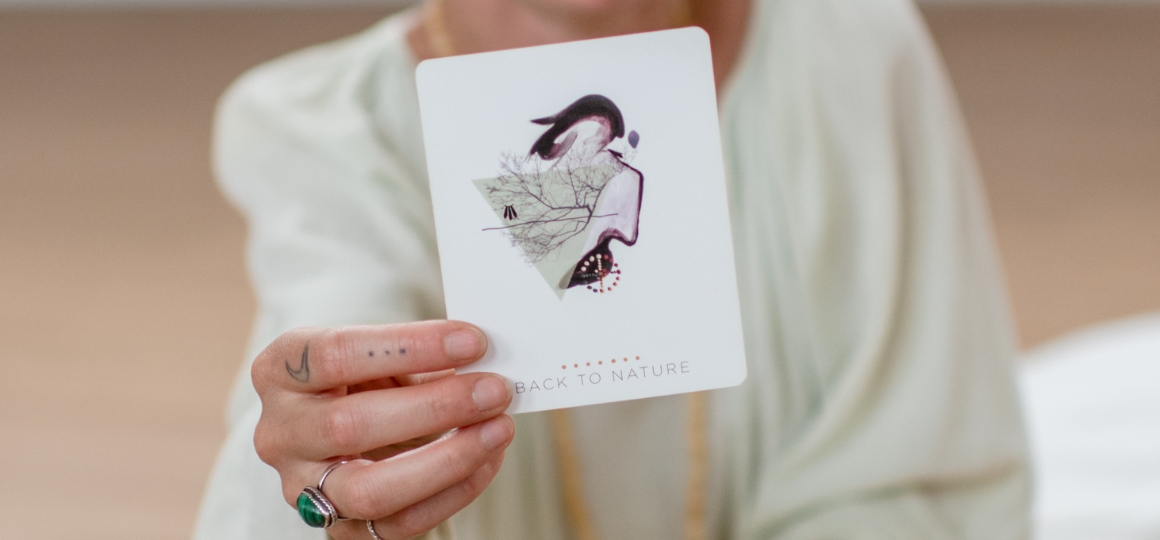 Person holding a card that says 'back to nature' during a workshop at De Nieuwe Yogaschool