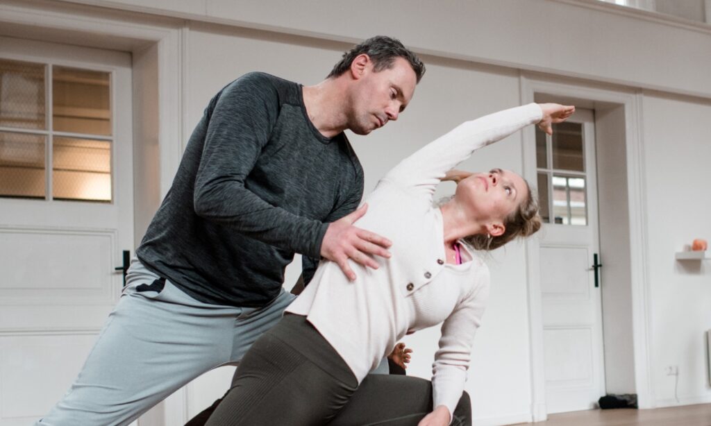 Student in a Vinyasa pose being adjusted by DNYS Academie teacher Johan Noorloos