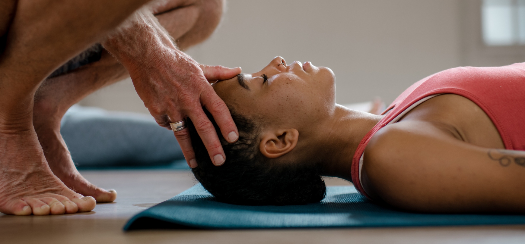 student die op yogamat ligt terwijl de yogadocent een drukpunt aanraking doet