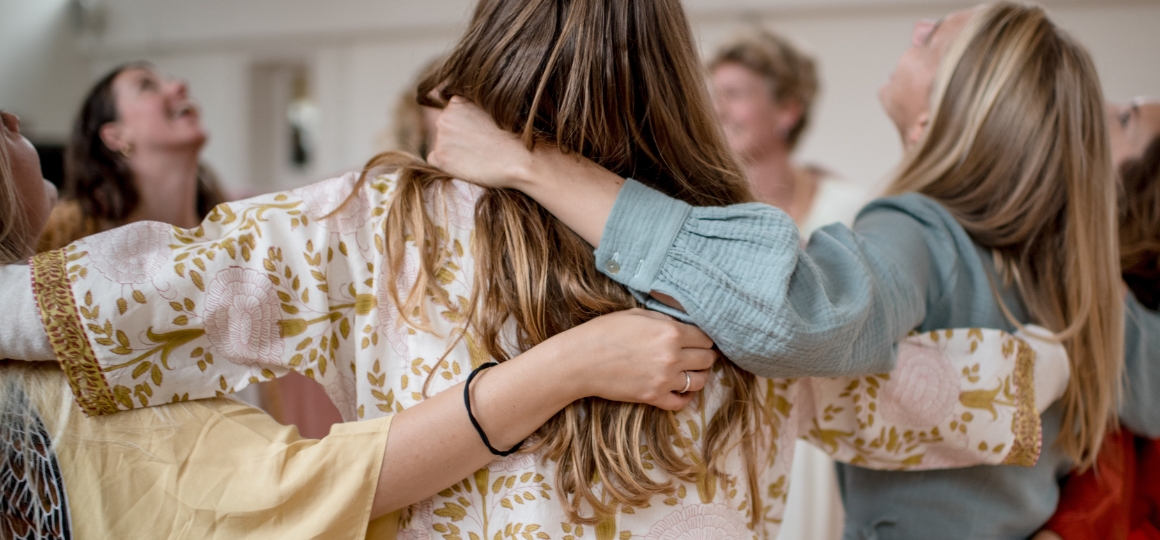 vrouwen die elkaar omhelzen in een cirkel in de studio van De Nieuwe Yogaschool