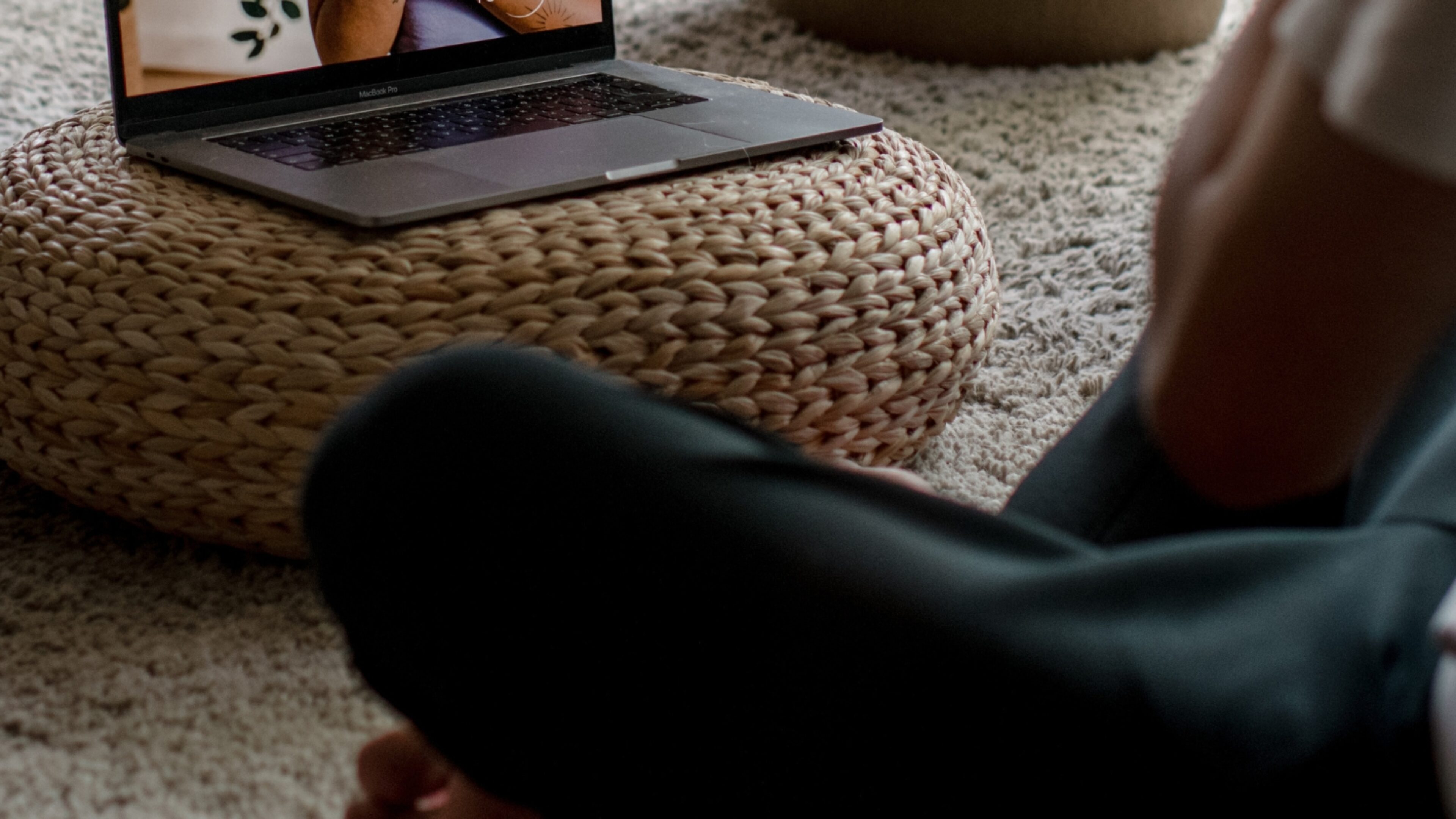 persoon die thuis yoga beoefent met een livestream les op de laptop