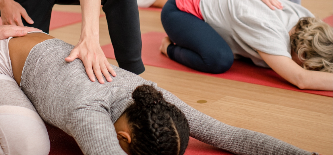 student die een andere student begeleidt tijdens yoga opleiding in De Nieuwe Yogaschool