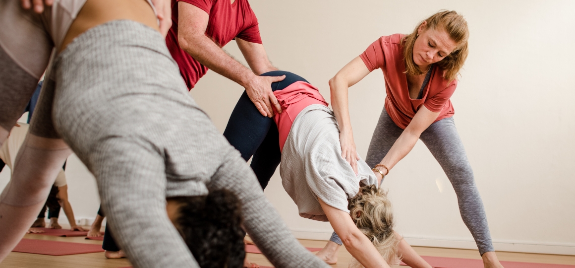 student die een adjustment doet bij een andere student tijdens yoga opleiding in De Nieuwe Yogaschool