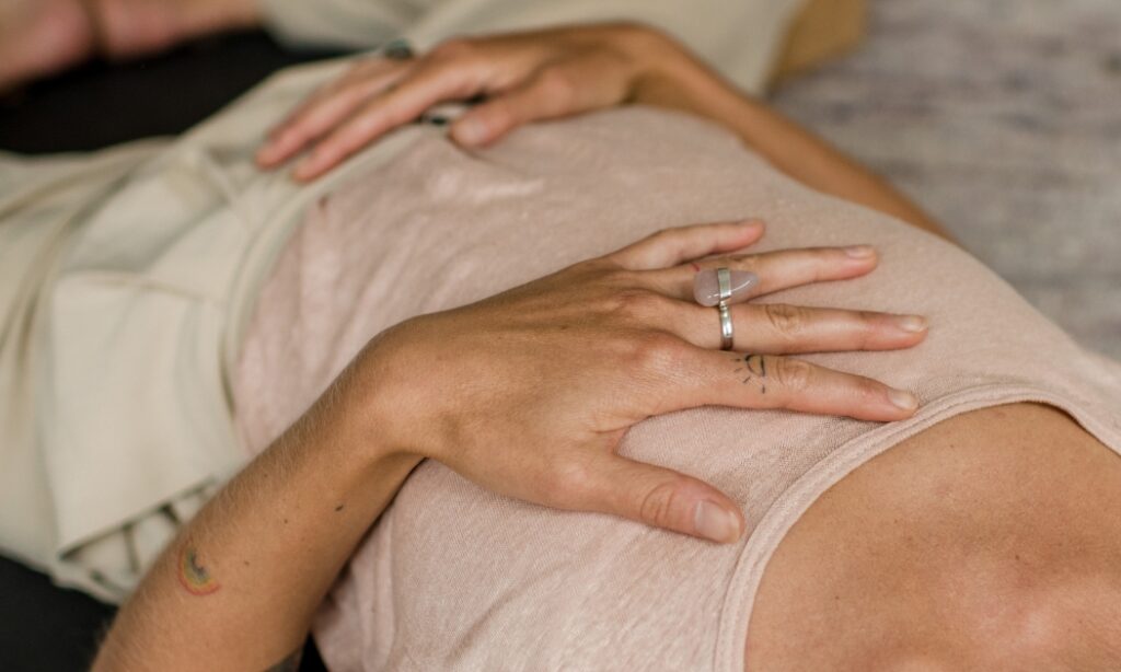 Vrouw die met hand op hart en buik ligt tijdens Yogatherapie opleiding van De Nieuwe Yogaschool