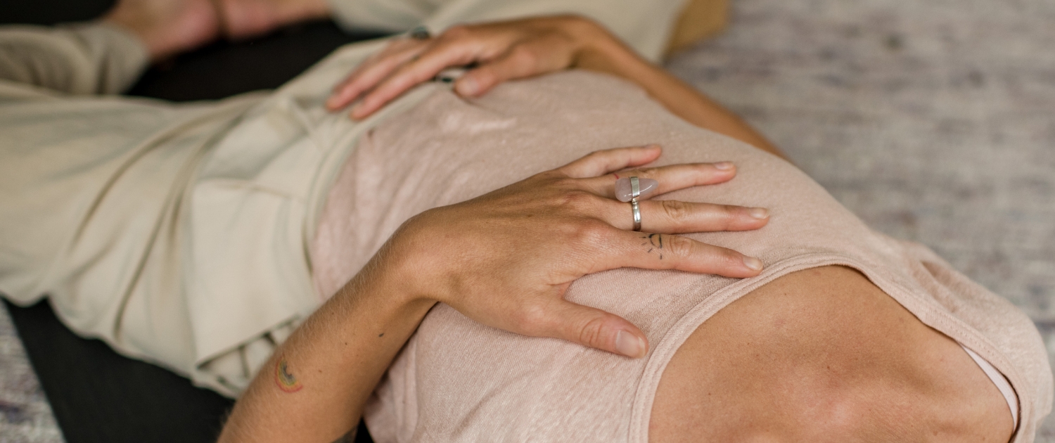 Vrouw die met hand op hart en buik ligt tijdens Yogatherapie opleiding van De Nieuwe Yogaschool